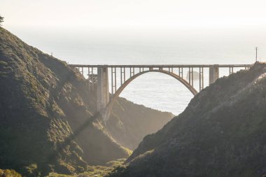 Kaliforniya 'nın göbeğinde sonbaharda günbatımında uzanan yol boyunca uzanan kemer köprüsü. Bixby Köprüsü, California State Route 1, Big Sur, CA, ABD.