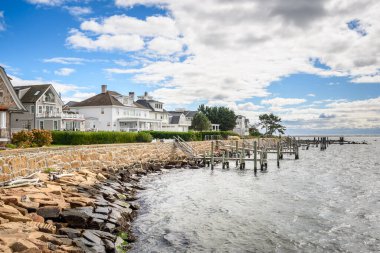 Row of traditonal houses with private jetty along a harbour on a partly cloudy autumn day. Stonington, CT, USA. clipart