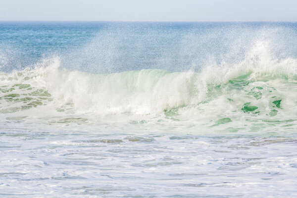 Передний вид большой волны океана, разбивающейся на берегу, выбрасывающей облака спрея в ветреный день. Марина, Калифорния, США.