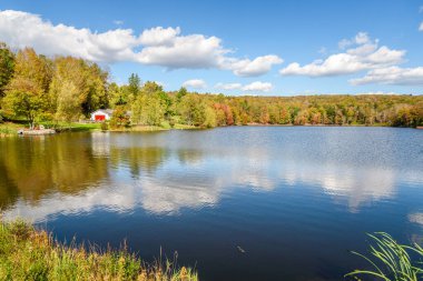 Açık bir sonbahar gününde, renkli ağaçlık kıyıları olan güzel bir gölde koy. Suyun ve sonbahar renklerinin yansıması. Catskill Dağları, New York, ABD.