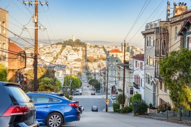 Açık bir sonbahar gününde San Francisco 'nun bir yerleşim bölgesinde apartman blokları ve evler ile kaplı dik bir cadde. Coit Kulesi görüş mesafesinde. Kaliforniya, ABD.