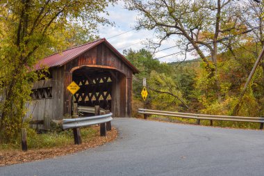 Eski patika, bulutlu bir sonbahar gününde dağlardaki bir nehri kaplayan köprüyü kaplıyordu. New Hampshire, ABD.