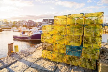 Sonbaharda gün batımında bir balıkçı limanında taş iskelede ıstakoz saksısı yığını. Rockport, MA, ABD.