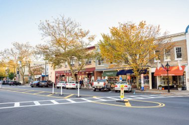 Sag Harbor, New York - 23 Ekim 2023: Günbatımında ana cadde boyunca dükkanları ve renkli sonbahar ağaçları olan geleneksel binalar. 1745 yılına kadar uzanan ana cadde Sag Limanı merkez merkezi olarak hizmet veriyor..