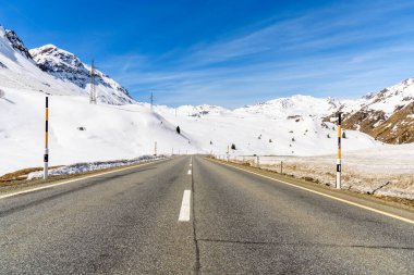 Güneşli bir günde İsviçre Alpleri 'ndeki karlı tepelerden geçen bir dağ geçidi yolu. Julier Geçidi, İsviçre.
