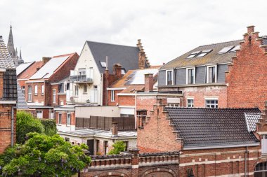 Bulutlu bir yaz gününde tarihi bir şehir merkezinde çatıları güneş panelleriyle kaplı eski tuğlalı evler. Ypres, Belçika.