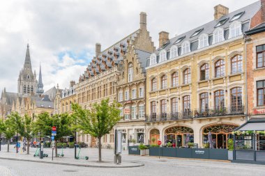Ypres, Belçika - 10 Temmuz 2024: Parçalı bulutlu gökyüzü altında Market Meydanı (Grote Markt) boyunca geleneksel mimari ve restoranlar