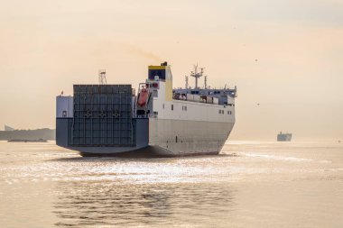 Büyük bir kargo gemisi yazın gün batımında limandan ayrılıyor. Rotterdam, Hollanda.