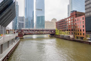 Bulutlu bir bahar gününde Chicago nehri boyunca çift katlı köprüden geçen metro treni. Chicago, Illinois, ABD.