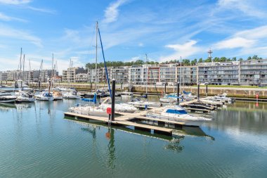 Güneşli bir yaz gününde modern apartman binalarıyla dolu bir marinada yatlar. Zeebrugge, Belçika.