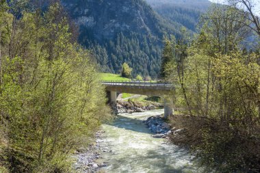 Güneşli bir bahar gününde İsviçre Alplerinde nehir boyunca uzanan beton yol köprüsü. Filisur, İsviçre.