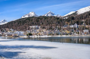 Güneşli bir bahar günü, kısmen donmuş gölün kıyısından St. Morizt manzarası. Grisonlar Kantonu, İsviçre.