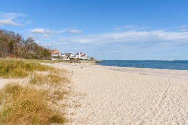 Terk edilmiş kumlu sahil ve mavi gökyüzünün altında kışın bulutlu deniz manzaralı evler. Hamptons, Long Isand, New York, ABD.