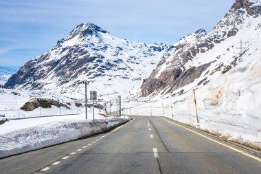 İsviçre Alpleri 'ndeki karlı bir dağ geçidinden geçen demiryolu boyunca uzanan boş dolambaçlı bir yol. Bernina Geçidi, İsviçre.
