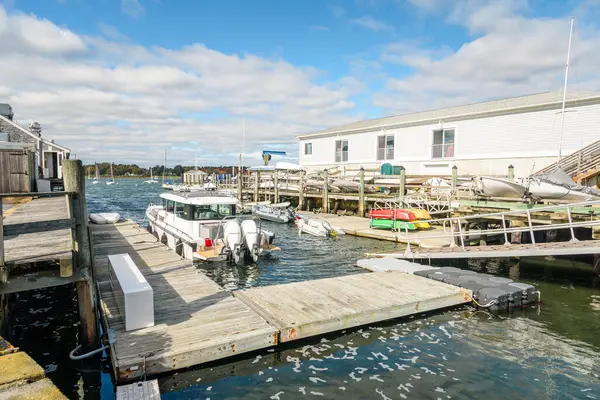 Güneşli bir sonbahar gününde, rıhtımdaki ahşap bir rıhtımda yüzen yelkenlilere ve botlara demirlenmiş tekneler. Stonington, CT, ABD.