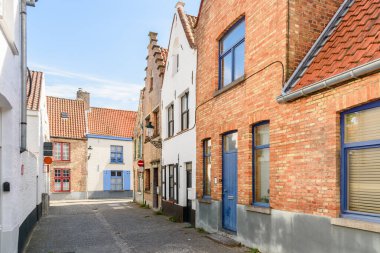 Güneşli bir yaz gününde tarihi bir şehir merkezinde geleneksel tuğla evlerle dolu bir cadde. Bruges, Belçika.