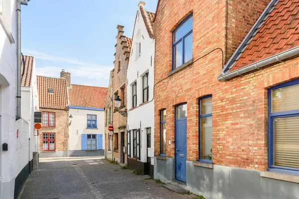 Güneşli bir yaz gününde tarihi bir şehir merkezinde geleneksel tuğla evlerle dolu bir cadde. Bruges, Belçika.