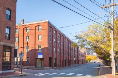 Güneşli bir sonbahar gününde eski tuğla binalar tarihi şehir merkezindeki bir cadde boyunca çatı katlarına ve ofislere dönüştürüldü. Portland, ME, ABD.