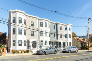 Güneşli bir sonbahar gününde banliyö yerleşim bölgesinde bir sokak boyunca yeni bir apartman. Boston, MA, ABD.