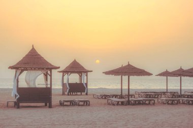 Günbatımında deniz ve şemsiyeli güzel tropikal plajlar seyahat ve tatil için