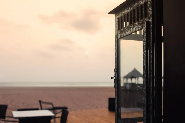 Gün batımında kumsalda şemsiyeli boş bir tahta sandalye ve masa. seyahat ve tatil geçmişi.