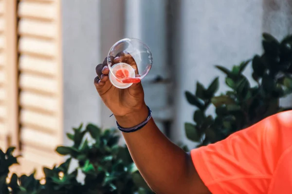 Elinde bir bardak portakal ve kırmızı meyve suyu tutan Afro-Amerikan adamın yakın görüntüsü.