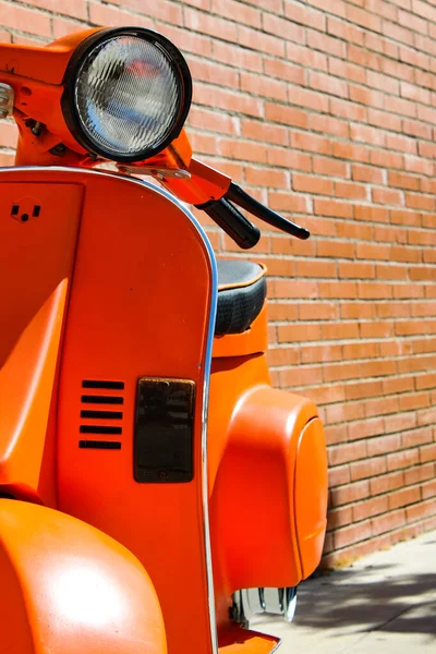 Duvarın arkasında turuncu motorsiklet.