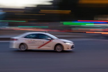 Madrid taksisinin hareketli görüntüsü alacakaranlıkta trafiğin yoğun olduğu bir caddede ilerliyor ve arka plan aydınlatma tarzıyla bulanıklaşıyor.