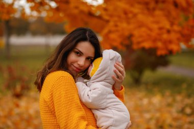 Mutlu aile anne ve bebek güler sonbaharda yapraklarla