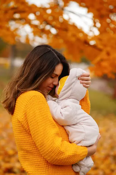 Mutlu aile anne ve bebek güler sonbaharda yapraklarla