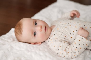 Beyaz bir battaniyenin üzerinde küçük bir bebek, yüzü yakın, Avrupalı görünümlü, çocuk