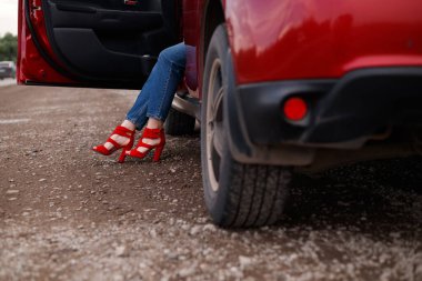 Kız beyaz bir iç mekanda kırmızı yüksek topuklu sandaletler giydi. Yeni ayakkabıların reklamı. Şık ve şık topuklar ve ayakkabılar.