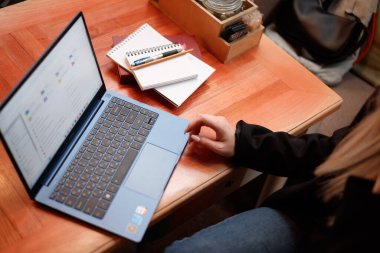 Bilgisayarın klavyesinde yazı yazan genç bayan öğretmen ya da öğrencinin eli kameranın önünde otururken ve görev sorularını cevaplarken