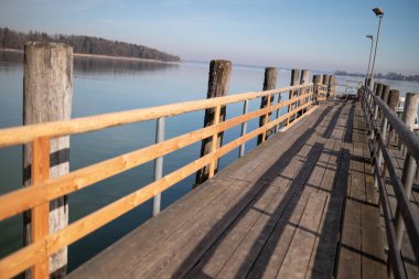 Kışın Almanya, Bavyera, Chiemsee 'deki tahta iskele. Güneşli bir gün, arka planda Bavyera Alpleri