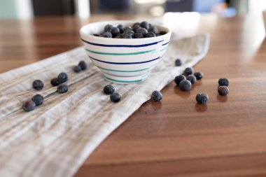 Kahverengi seramik kase taze olgun yaban mersini ve mutfak masasında masa örtüsü.