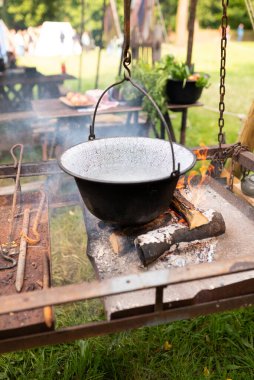 Çaydanlık yürüyüşü, şenlik ateşinde bowling. Kazıkta kazanda balık çorbası kaynıyor. Seyahat, turizm, piknik pişirme, kazanda yemek pişirme, ateş ve duman.