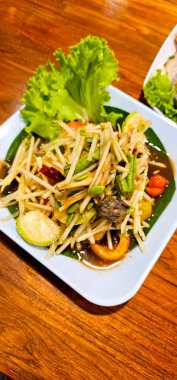 yeşil papaya salatası, tuzlanmış yengeç ve sebze. Restorandaki ahşap masada.