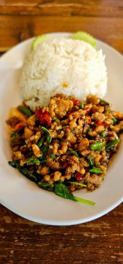 Tahta arka planda pirinçli kızarmış domuz ve fesleğen, Tayland yemeği.