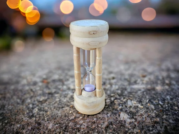 Wooden hourglass isolated on the beach. Sand clock on the beach sand with bokeh in the background.