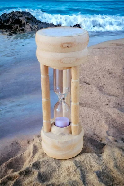 Wooden hourglass isolated on the beach. Sand clock on the beach sand.