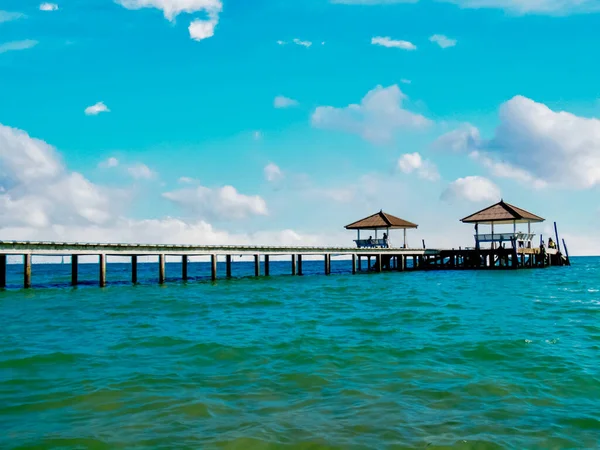 Wooden jetty on the tropical beach with blue sky background.