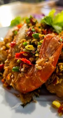 Baharatlı kızarmış karides, acı biberli karides, kuşlu kızarmış karides ve ahşap tabakta kırmızı biber.