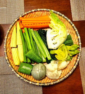 Sebzeler bir sepetin içinde, restoranın ahşap masasında, manzaranın üstünde.