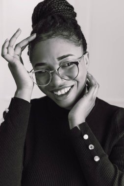 Beyaz arka planda gülümseyen ve mutlu, siyah bluz giyen Afro-Amerikan bir kadının siyah beyaz portresi.