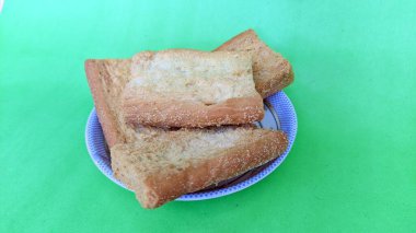 Yeşil bir yüzey üzerinde bir tabak kızarmış ekmek.
