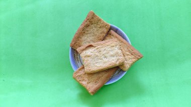 Yeşil bir yüzey üzerinde bir tabak kızarmış ekmek.