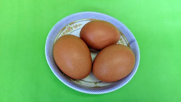 Bovenaanzicht Van Rauwe Bruine Eieren Een Plaat Geïsoleerd Groene Achtergrond — Stockfoto