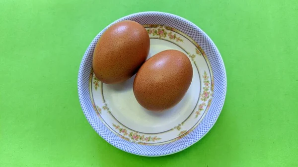 Bovenaanzicht Van Twee Rauwe Bruine Eieren Een Plaat Geïsoleerd Groene — Stockfoto