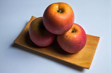 Beyaz arka planda izole edilmiş ahşap tabakta kırmızı elmaları kapat