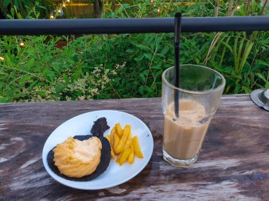 Patates kızartması, profiterol, soslar ve çikolatalı içecekler masada..